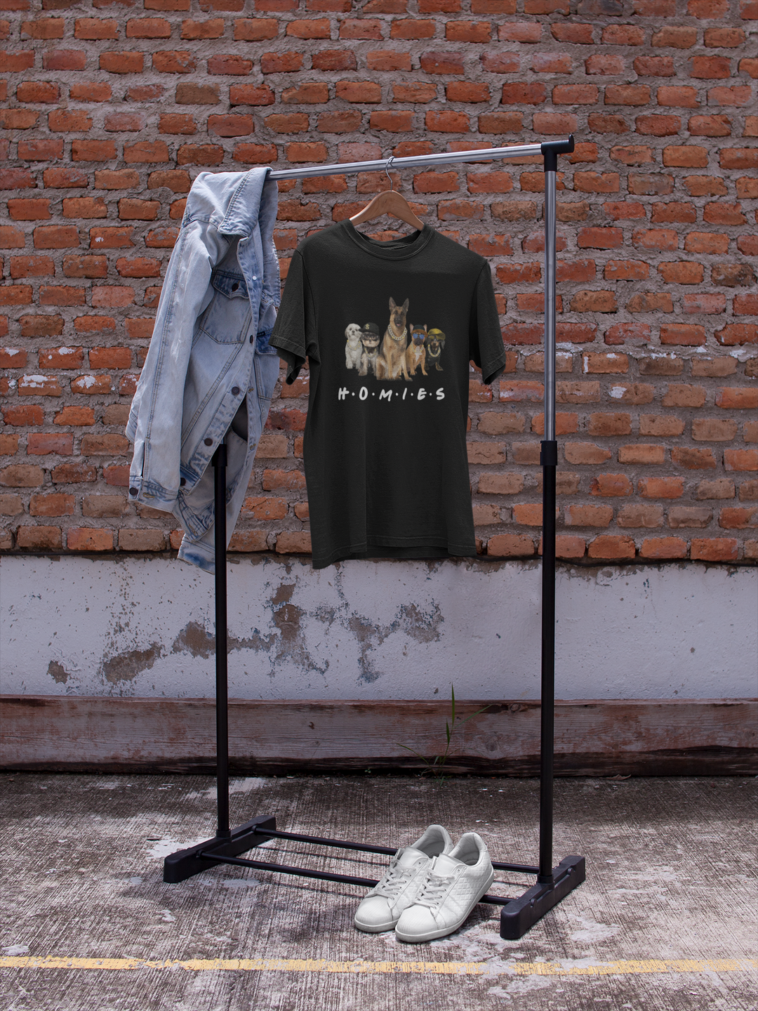 Black t-shirt with graphic design on a black clothing rack against a brick wall.